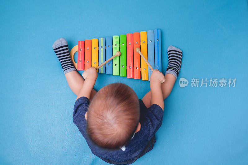 鸟瞰图可爱的小亚洲18个月/ 1岁的婴儿男孩孩子拿木棍和弹奏乐器彩色木制玩具木琴